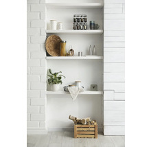 Weißes Einbauregal mit Küchenutensilien, Pflanze und Holzkiste mit Birkenholz vor einer Ziegel- und Paneelwand.