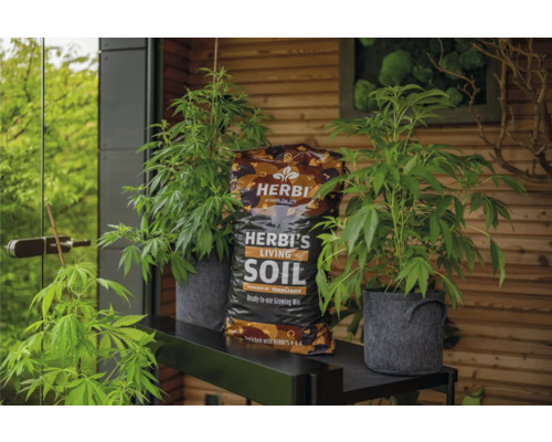 Herbi's Living Soil Pflanzenerde mit Pflanzen in Töpfen auf einem Regal.