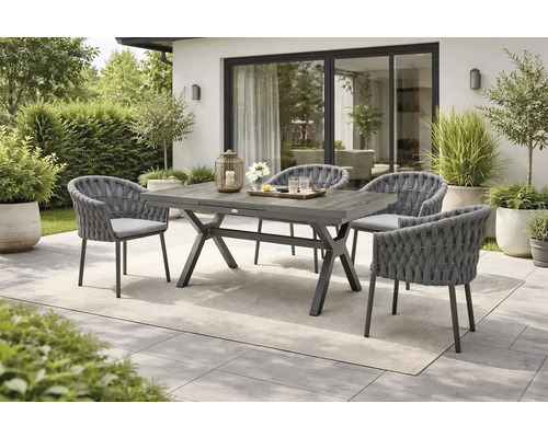 Gartenszene mit Esstisch aus Holz und vier Stühlen mit geflochtenen Details.