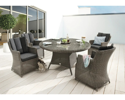 Gartenszene mit rundem Esstisch und vier Korbsesseln im Außenbereich