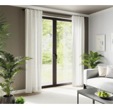 Wohnzimmer mit weißen Vorhängen vor einer Terrassentür und Zimmerpflanzen