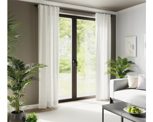 Wohnzimmer mit weißen Vorhängen vor einer Terrassentür und Zimmerpflanzen