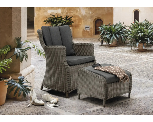 Geflochtener Sessel und Hocker mit Polsterauflagen in einem Innenhof