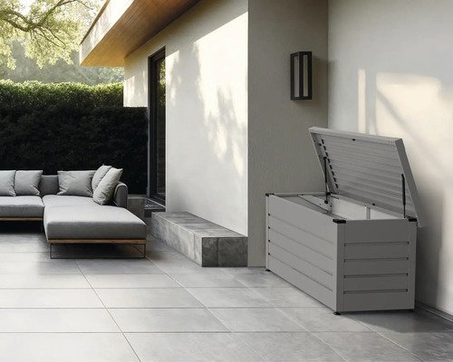 Gartenbox mit geöffnetem Deckel auf einer Terrasse neben Gartenmöbeln