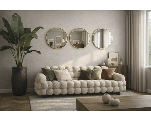 Wohnzimmer mit gepolstertem Sofa, Zierkissen, Zimmerpflanze in einem Topf und drei runden Spiegeln an der Wand.