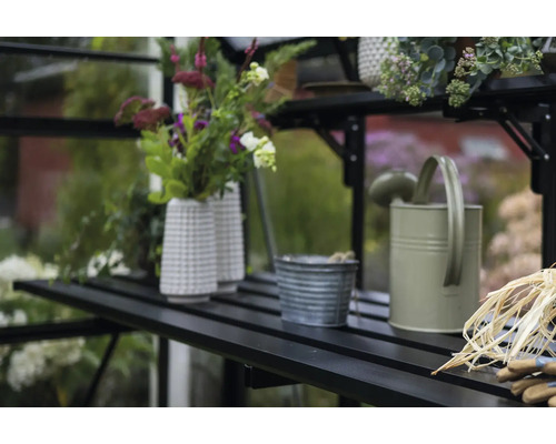 Klappbarer Lamellentisch Halls Icon 8 9,7 m² 356 x 55 cm schwarz Gartenszene mit Gießkanne, Blumentöpfen und Gartenzubehör auf einem Regal im Gewächshaus.