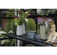 Gartenszene mit Gießkanne, Blumentöpfen und Gartenzubehör auf einem Regal im Gewächshaus.