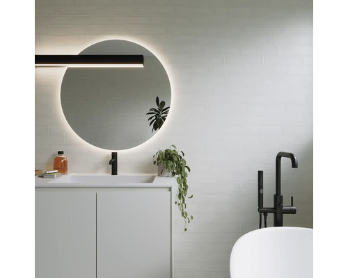 Modernes Badezimmer mit rundem Spiegel, Waschtisch, Armatur und Badewanne.