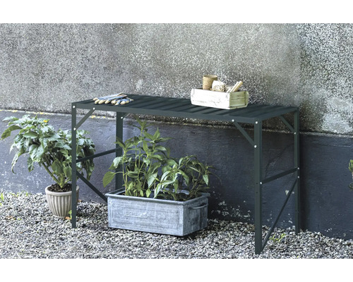 Gartentisch mit Pflanzen, Gartenwerkzeugen und Handschuhen im Außenbereich