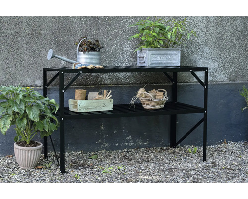 Gartentisch mit zwei Ablageflächen und Gartenzubehör wie Gießkanne und Pflanzen