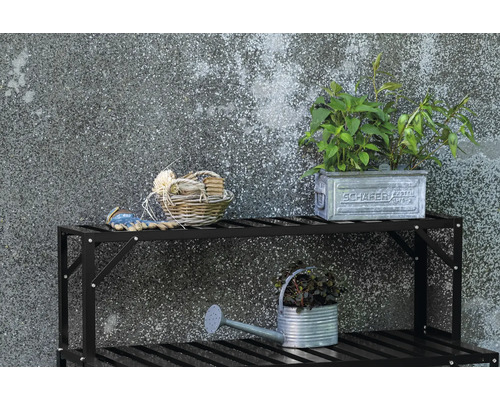 Gartenszene mit Pflanzenregal, Zinkgießkanne, Pflanzen und Gartenzubehör