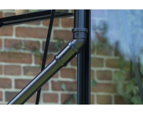 Detailaufnahme eines schwarzen Metallrohrs mit Verbindungselementen an einem Gewächshaus.