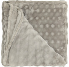 Gefaltete, weiche Wohndecke mit Noppenstruktur aus Polyester.