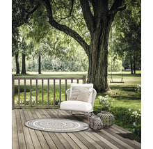Szene im Garten mit Gartenteppich, Sessel, Kissen und Laternen auf einer Holzterrasse