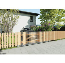 Moderner Lattenzaun aus Holz mit integriertem Schiebetor vor einem Wohnhaus und Garten. Senkrechte Holzlatten auf gepflastertem Boden.