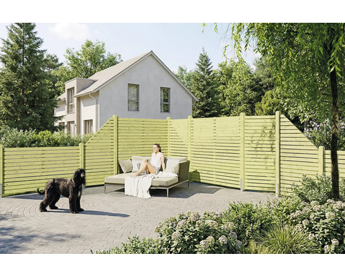 Sichtschutzzaun aus Holz mit horizontalen Lamellen auf einer gepflasterten Terrasse mit Gartenmöbeln und einem Hund.