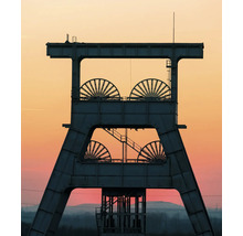 Silhouette eines Fördergerüsts aus Stahl mit vier großen Seilscheiben vor einem Abendhimmel.