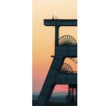 Industrielles Fördergerüst einer Zeche mit zwei Seilscheiben vor einem weiten Abendhimmel.