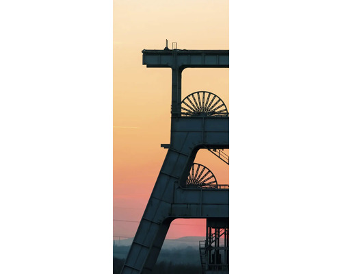 Industrielles Fördergerüst einer Zeche mit zwei Seilscheiben vor einem weiten Abendhimmel.