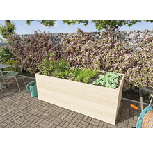 Rechteckiges Hochbeet aus hellem Holz mit Kräutern und Gemüse auf einer gepflasterten Terrasse vor einer bepflanzten Steinmauer.
