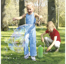 Zwei Kinder spielen im Park mit einem Seifenblasenset und erzeugen große Seifenblasen.