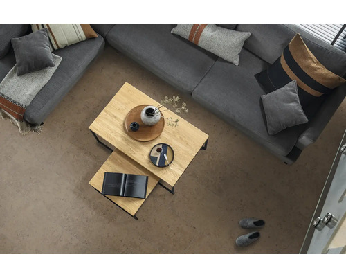 Strukturierte Bodenfliesen in Steinoptik im hellen Wohnzimmer mit grauem Sofa, hölzernen Couchtischen und dekorativen Kissen.