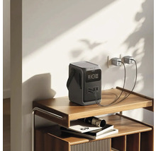 Tragbare Powerstation auf einem Regal, angeschlossen an eine Wandsteckdose mit zwei USB-Kabeln.