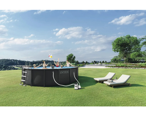 Rundes Intex Frame Pool im Garten mit spielenden Personen, inklusive Leiter, Filterpumpe und zwei Sonnenliegen auf einer Rasenfläche.