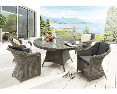 Gartenmöbel-Set aus grauem Geflecht mit rundem Glastisch und vier Sesseln inklusive Sitzkissen auf einer hellen Terrasse.