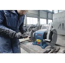 Bosch Professional Doppelschleifer in einer Werkstatt, ein Handwerker schärft ein Werkzeug mit Funkenflug.
