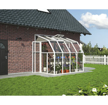 Anlehngewächshaus aus weißem Aluminium und Glas mit Dachfenster, montiert an einer Ziegelwand im Garten.