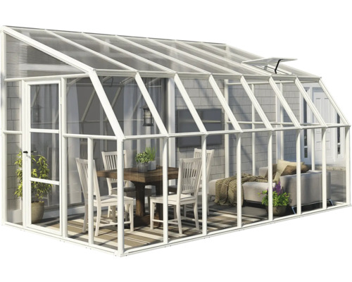 Anlehngewächshaus mit weißem Aluminiumrahmen und Glaswänden, eingerichtet mit Esstisch, Stühlen und Sofa als heller Wohnraum im Freien.