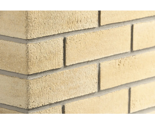 Strukturierte Mauer aus Kalksandstein mit Mörtelfugen an einer Wandecke.