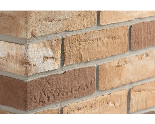 Strukturierte Verblender in Beige- und Brauntönen an einer Wandecke mit grauen Mörtelfugen.