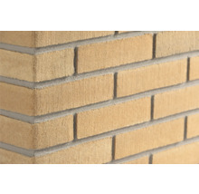 Gelbe Klinker-Riemchen in Sandstein-Optik für die Wandverkleidung, sandgestrahlte Oberfläche, Eckansicht einer Mauer.