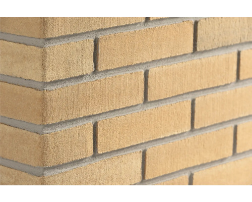 Gelbe Klinker-Riemchen in Sandstein-Optik für die Wandverkleidung, sandgestrahlte Oberfläche, Eckansicht einer Mauer.