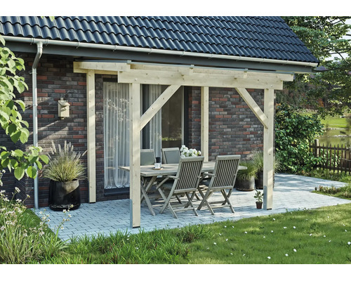 Terrassenüberdachung aus hellem Holz an einer Klinkerwand, darunter eine Sitzgruppe mit Tisch und vier Stühlen auf einer gepflasterten Terrasse.