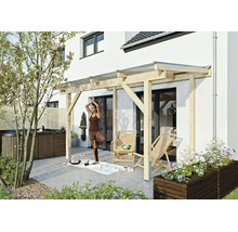 Moderne Terrassenüberdachung aus hellem Holz an einer Hauswand, davor eine gepflasterte Terrasse mit Gartenmöbeln und Whirlpool.