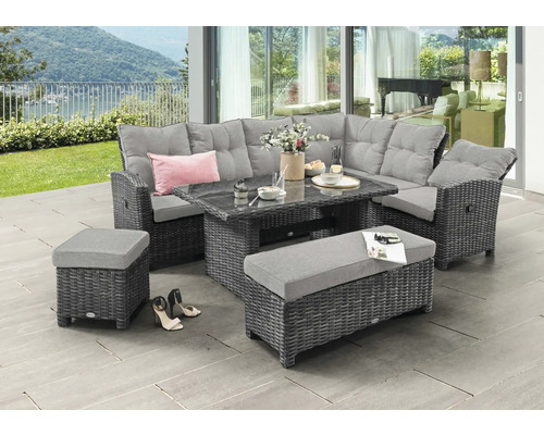 Garten-Lounge-Set aus grauem Polyrattan mit Ecksofa, Glastisch, Bank und Hocker auf einer hellen Terrasse mit Blick ins Grüne.