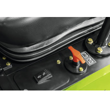 Bedienpanel einer Baumaschine mit orangefarbenem Batterietrennschalter und schwarzem Wippschalter neben dem Sitz.