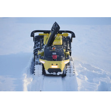 Gelbe Roboter-Schneefräse mit Kettenantrieb und Auswurfschacht räumt einen Pfad durch tiefen Schnee.