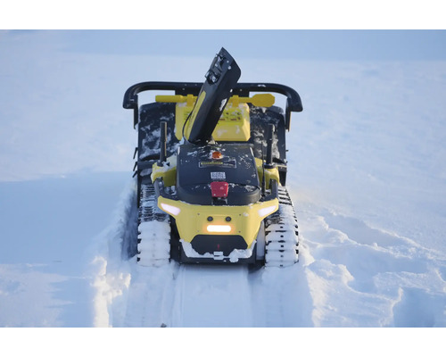 Gelbe Roboter-Schneefräse mit Kettenantrieb und Auswurfschacht räumt einen Pfad durch tiefen Schnee.