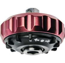 Rote Handknarre aus Metall mit schwarzem Sockel, geriffeltem Griff und Umschaltfunktion durch Pfeilsymbole.