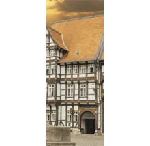 Historisches Fachwerkhaus mit dunklen Holzbalken, weißen Gefachen und einem Dach aus orangefarbenen Tondachziegeln.