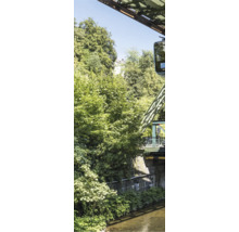 Wuppertaler Schwebebahn über einem Fluss mit dichten grünen Bäumen und Stahlkonstruktionen.