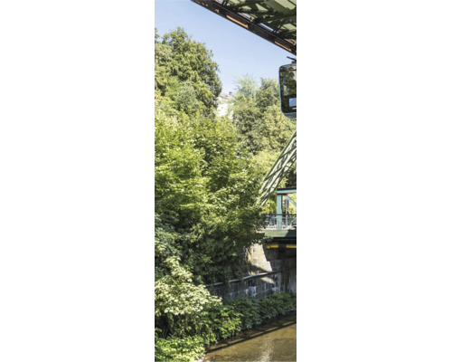 Wuppertaler Schwebebahn über einem Fluss mit dichten grünen Bäumen und Stahlkonstruktionen.