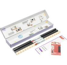 d-c-fix Designfolie Set in einer geöffneten Verpackung mit schwarzen Rollen, einer gemusterten Rolle, Faltschablone und Verarbeitungsset.
