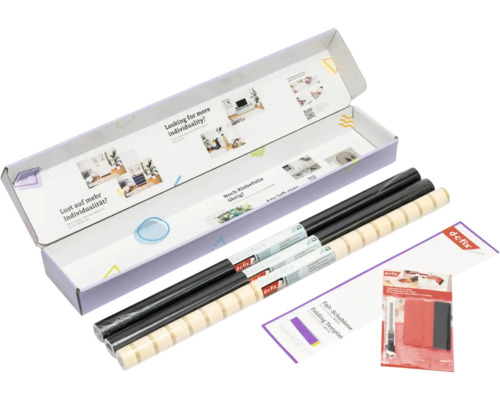 d-c-fix Designfolie Set in einer geöffneten Verpackung mit schwarzen Rollen, einer gemusterten Rolle, Faltschablone und Verarbeitungsset.