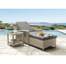 Polyrattan-Sonnenliege mit grauen Polstern und passendem Beistelltisch auf einer Terrasse am Pool mit Meerblick.