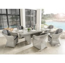 Modernes Gartenmöbel-Set aus hellem Geflecht mit Glas-Esstisch und sechs Sesseln inklusive grauer Auflagen auf einer hellen, organisierten Terrasse.